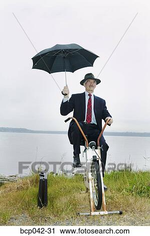 Businessman riding stationary bike near lake View Large Photo Image Stock Image - Businessman riding stationary bike near lake. Fotosearch