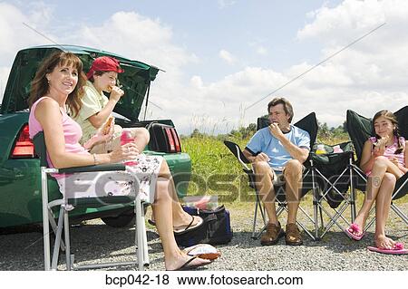 Family having picnic lunch outside car View Large Photo Image Stock Photo - Family having picnic lunch outside car. Fotosearch