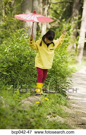 Girl with parasol balancing on log View Large Photo Image Stock Photo - Girl with parasol balancing on log. Fotosearch