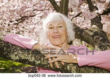 Older woman posing with flowering tree View Large Photo Image Stock Photo - Older woman posing with flowering tree. Fotosearch