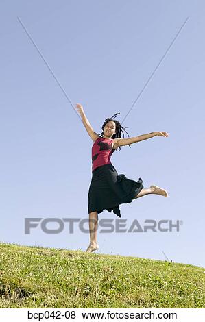 Young woman dancing on grassy hill View Large Photo Image Stock Photo - Young woman dancing on grassy hill. Fotosearch