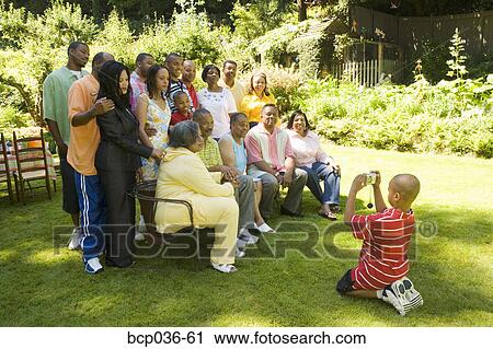 Stock Image - Boy photographing his family outdoors. Fotosearch