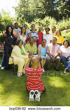 Stock Image - Boy photographing his family outdoors. Fotosearch