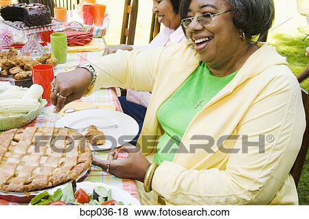 Stock Photo - Digging into dessert at a picnic. Fotosearch