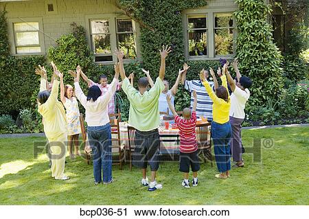 Stock Image - Family with upraised arms at picnic. Fotosearch