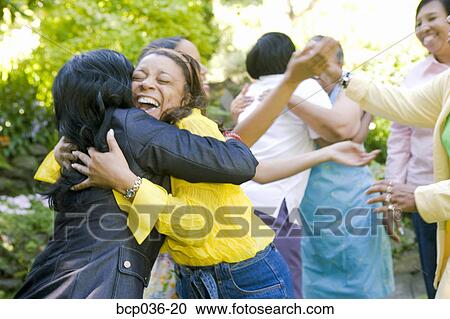 Stock Image - Females hugging outdoors. Fotosearch