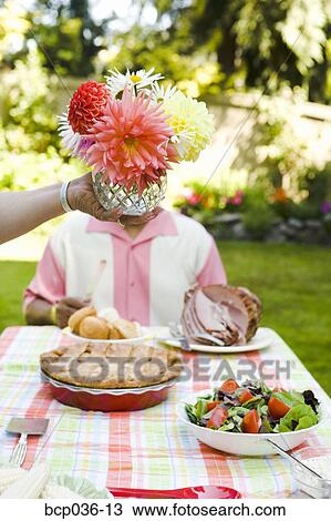 Stock Image - Flower centerpiece held above picnic table. Fotosearch