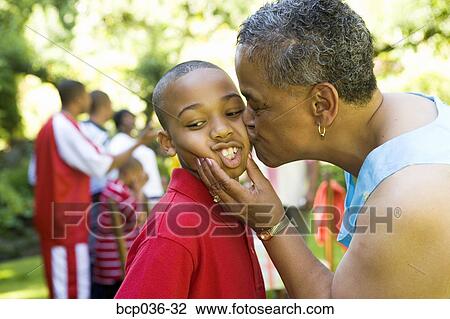 Stock Image - Grandmother kissing young boy. Fotosearch