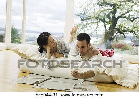 Couple on bed looking at newspaper View Large Photo Image Stock Image - Couple on bed looking at newspaper. Fotosearch
