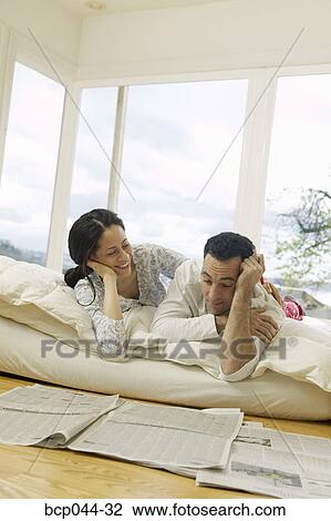 Couple on bed looking at newspaper View Large Photo Image Stock Image - Couple on bed looking at newspaper. Fotosearch