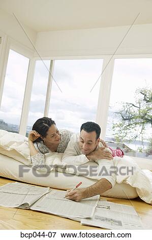 Couple on bed looking at newspaper View Large Photo Image Stock Photo - Couple on bed looking at newspaper. Fotosearch