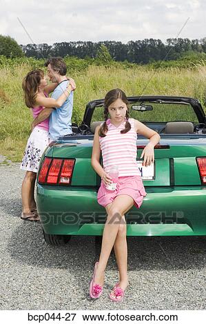 Stock Photo - Unhappy daughter of affectionate parents. Fotosearch