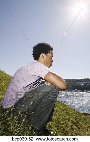 Stock Image - Young man sitting and thinking. Fotosearch