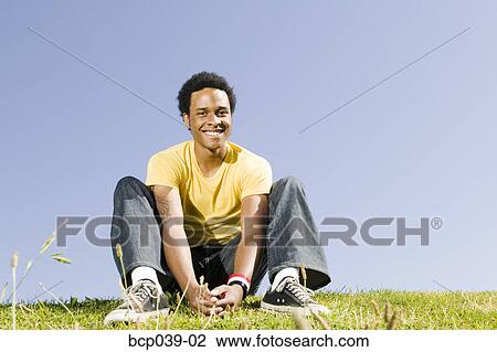 Young man sitting outdoors View Large Photo Image Stock Image - Young man sitting outdoors. Fotosearch