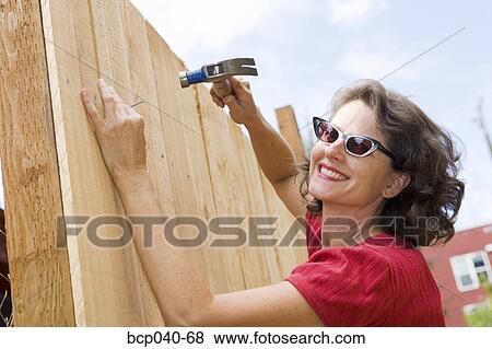Stock Photo - Closeup of woman building fence. Fotosearch