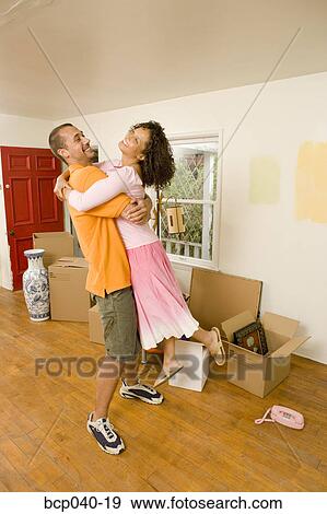 Couple embracing in new home with boxes View Large Photo Image Stock Photo - Couple embracing in new home with boxes. Fotosearch