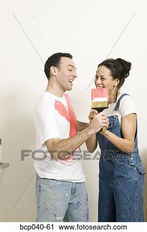 Couple playfully struggling with paintbrush View Large Photo Image Stock Image - Couple playfully struggling with paintbrush. Fotosearch