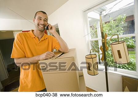 Man in new home on mobile phone View Large Photo Image Stock Photo - Man in new home on mobile phone. Fotosearch