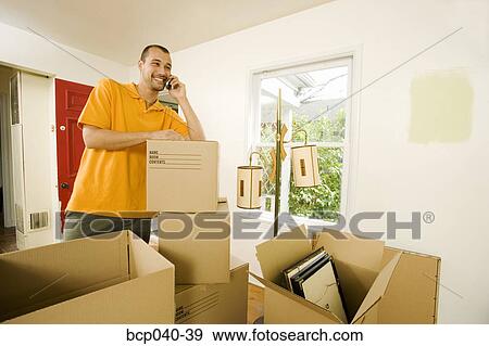Man in new home on mobile phone View Large Photo Image Stock Photo - Man in new home on mobile phone. Fotosearch
