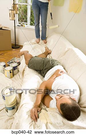 Man on couch and woman painting View Large Photo Image Stock Image - Man on couch and woman painting. Fotosearch