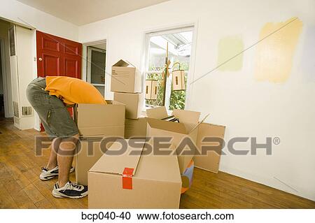 Stock Image - Man with moving boxes in new home. Fotosearch