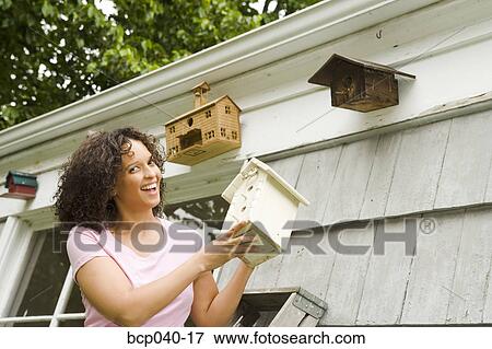Smiling woman adding to birdhouse collection View Large Photo Image Stock Photo - Smiling woman adding to birdhouse collection. Fotosearch