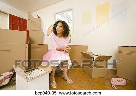 Stock Photography - Woman in new home with moving boxes. Fotosearch