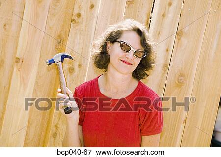 Woman posing with hammer and fence View Large Photo Image Stock Photo - Woman posing with hammer and fence. Fotosearch