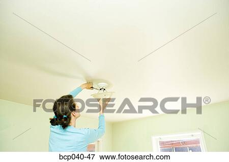 Woman repairing light fixture on ceiling View Large Photo Image Stock Photo - Woman repairing light fixture on ceiling. Fotosearch