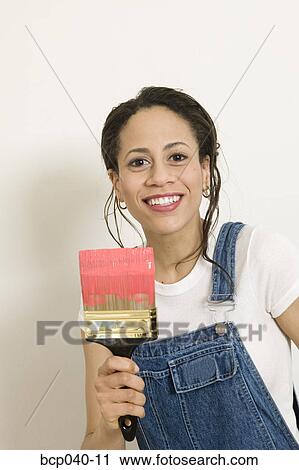 Stock Image - Young woman posing with paintbrush. Fotosearch
