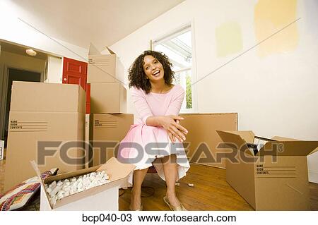 Stock Image - Young woman with moving boxes. Fotosearch