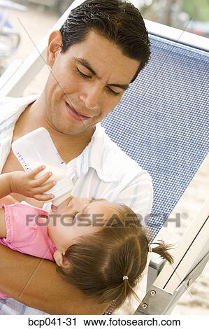 Dad holding daughter drinking from bottle View Large Photo Image Stock Image - Dad holding daughter drinking from bottle. Fotosearch