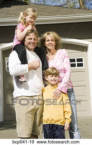 Stock Photo - Family portrait outside house. Fotosearch