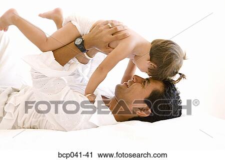 Father playing with toddler on bed View Large Photo Image Stock Image - Father playing with toddler on bed. Fotosearch