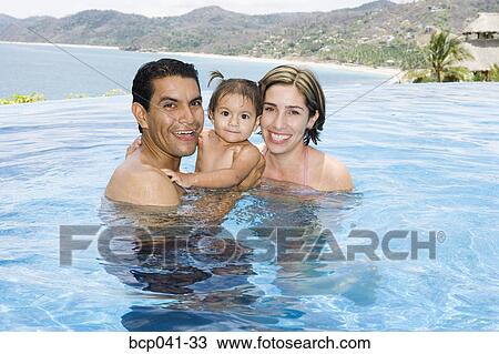 Stock Image - Parents and toddler in tropical pool. Fotosearch