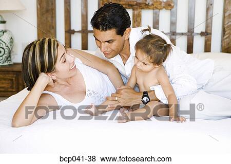 Parents and toddler lying on bed View Large Photo Image Stock Photo - Parents and toddler lying on bed. Fotosearch