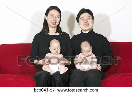 Parents with two infants on couch View Large Photo Image Stock Photo - Parents with two infants on couch. Fotosearch
