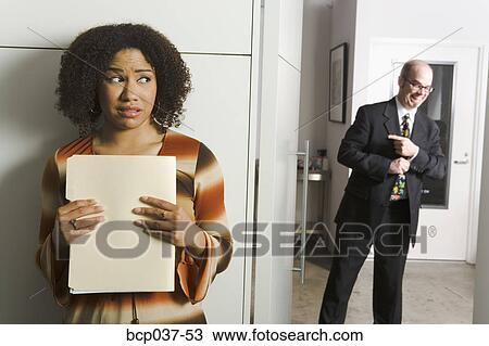 Stock Image - Geeky man pursuing female co-worker. Fotosearch