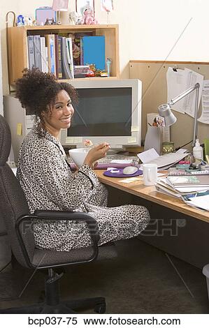 Stock Photography - Woman eating breakfast in home office. Fotosearch