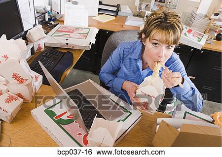 Young woman eating at her desk View Large Photo Image Stock Photograph - Young woman eating at her desk. Fotosearch