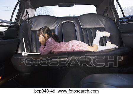 Girl using laptop in back seat of car View Large Photo Image Stock Photography - Girl using laptop in back seat of car. Fotosearch