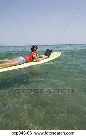 Little girl using laptop on surfboard View Large Photo Image Stock Photograph - Little girl using laptop on surfboard. Fotosearch