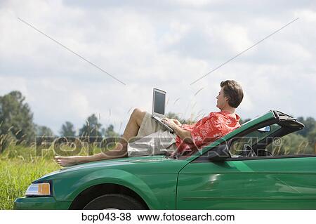 Man on car hood using laptop View Large Photo Image Stock Photo - Man on car hood using laptop. Fotosearch