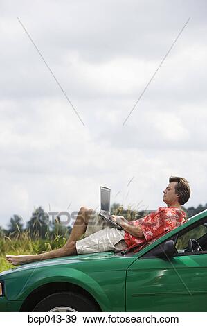 Man on car hood using laptop View Large Photo Image Stock Photo - Man on car hood using laptop. Fotosearch