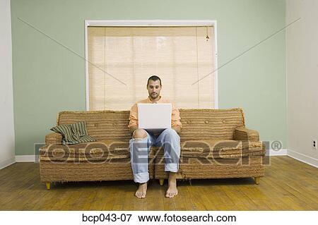 Man using laptop in living room View Large Photo Image Stock Photo - Man using laptop in living room. Fotosearch