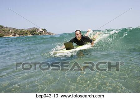 Man using laptop while paddling surfboard View Large Photo Image Stock Image - Man using laptop while paddling surfboard. Fotosearch