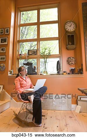 Stock Photography - Thoughtful woman using laptop at home. Fotosearch