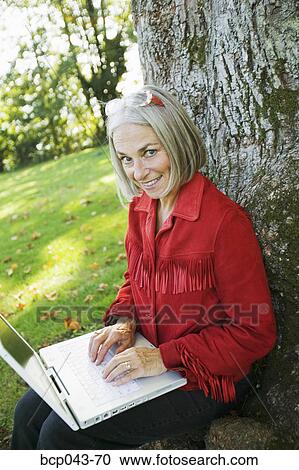 Woman with tree using laptop View Large Photo Image Stock Image - Woman with tree using laptop. Fotosearch