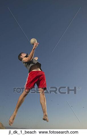 Low angle view of a young man jumping up in the air playing volleyball View Large Photo Image Stock Image - Low angle view of a young man jumping up in the air playing volleyball. Fotosearch