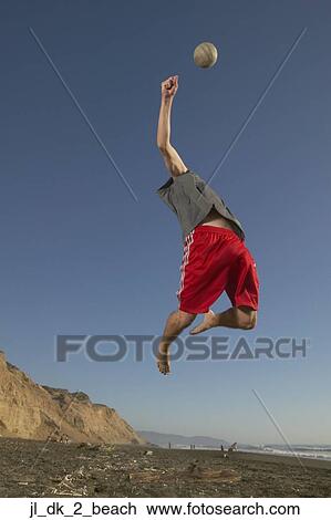 Low angle view of a young man jumping up in the air reaching for a volleyball View Large Photo Image Stock Image - Low angle view of a young man jumping up in the air reaching for a volleyball. Fotosearch